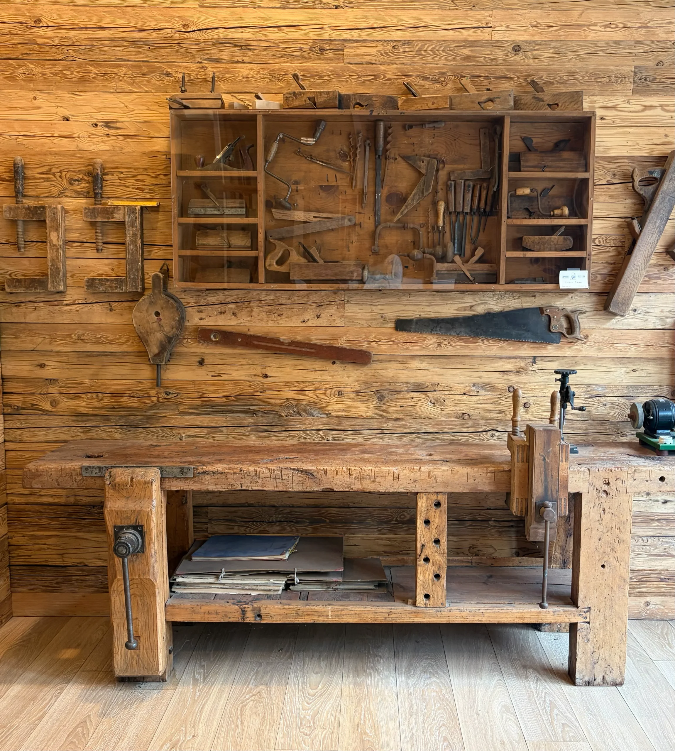 Antiguo taller de fusteria con banco de trabajo de madera, herramientas tradicionales y estanterías en pared de madera