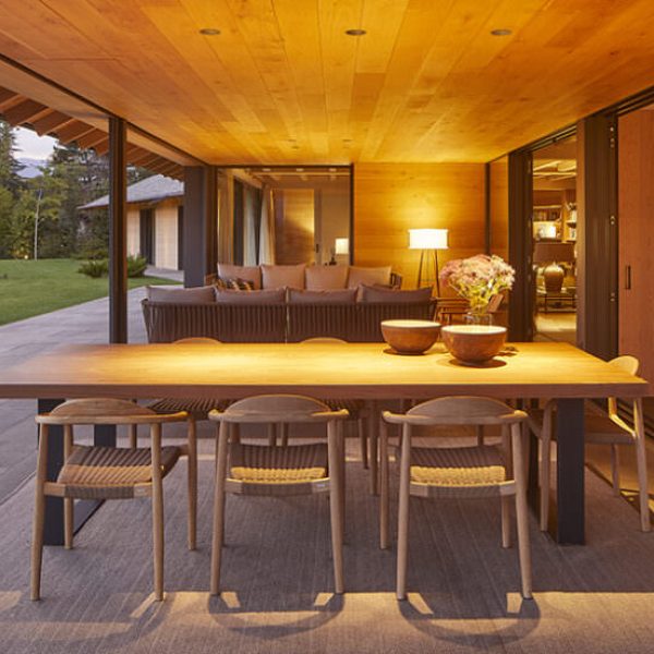Terraza exterior de lujo con comedor de madera y sala de estar, vistas a la montaña al atardecer, diseño moderno