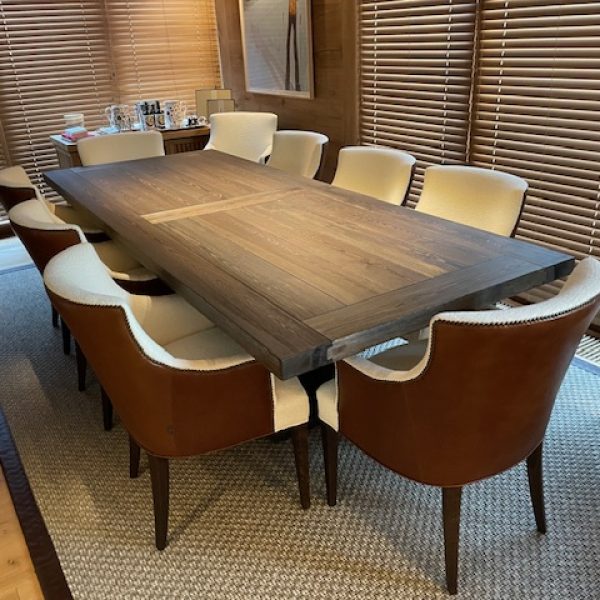 Comedor elegante con mesa de madera oscura y sillas tapizadas en cuero marrón y tela clara, persianas de madera