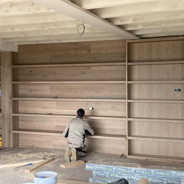 Carpintero instalando estanterías de madera a medida en la Cerdanya, mostrando la artesanía de Adam Fusteria.